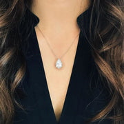 Teardrop-shaped diamond necklace worn by a person with long hair and a dark outfit.